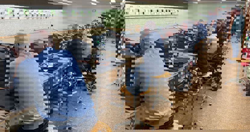 Lokal med skyttetavlor, sittande skyttar på rad med luftgevär