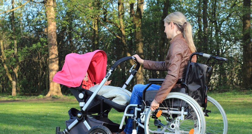 En kvinna i rullstol, med barnvagn