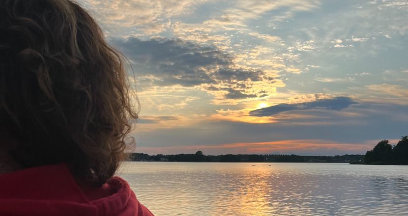 Kvinna vid en solnedgång vid havet. Foto.