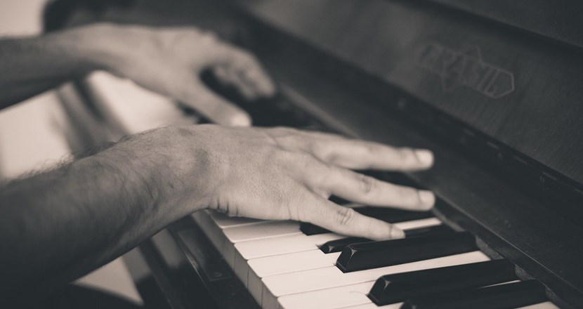 Två händer som spelar på ett piano. Foto.