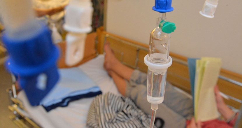 Fötterna på en patient som får dropp och ligger i en sjukhussäng. Foto.