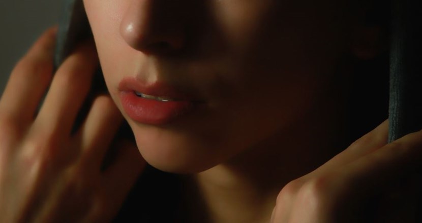 Närbild på en ung kvinnas mun med händerna nära ansiktet