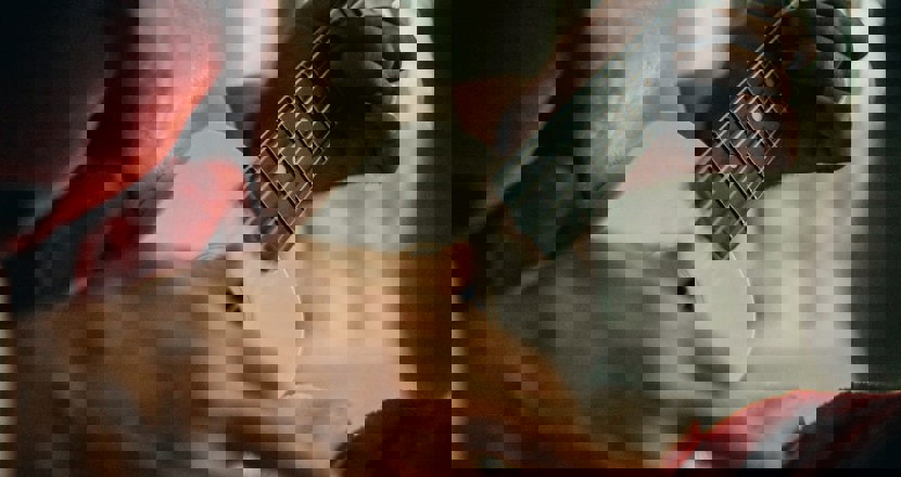 Närbild på tomteklädd man som spelar på lite gitarr, man ser bara instrumentet och händerna.