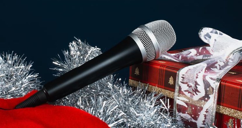 En mikrofon som ligger på julglitter och annat julpynt och väntar på att bli upplockad för att användas vid ett jultal.