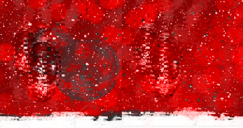 Röda julgranskulor mot en röd och vit bakgrund. Foto.