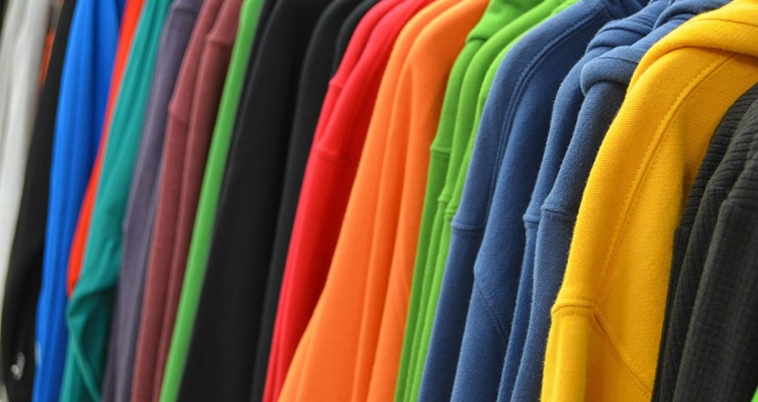 Tips om kläder för funktionshindrade. En bild med färgglada kläder som händer på galgar. Foto.