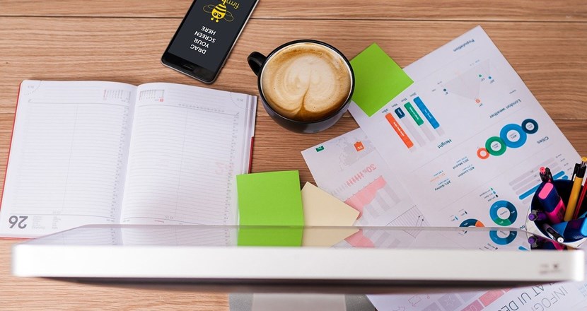 Skrivbord med kalender, papper, mobil och en kopp kaffe. Foto: Pixabay 
