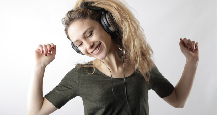 Tjej i långt blont hår och armarna i luften som dansar loss. Foto.