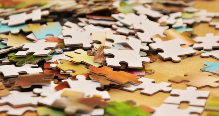 Pusselbitar i olika färger i en osorterad hög på ett bord.