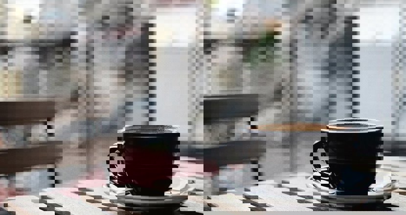 En svart kaffekopp står på ett bord med en suddig bakgrund. Foto.