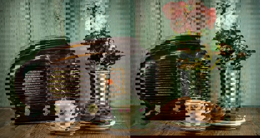 En retroradio, en kopp kaffe, bullar och en blomma. Foto.