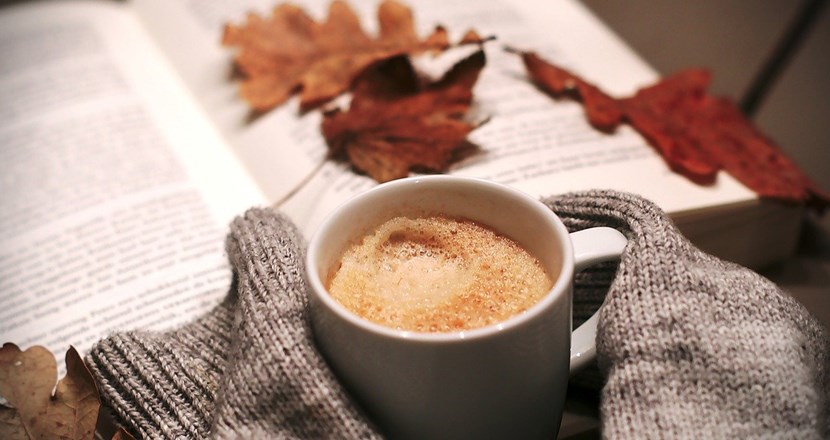 En kopp kaffe och en uppslagen bok med några torra ekblad liggande på boksidan. Foto. Bild: pixabay.com.