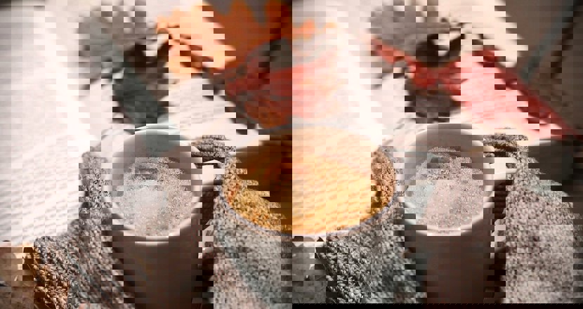 En kopp kaffe och en uppslagen bok med några torra ekblad liggande på boksidan. Foto. Bild: pixabay.com.