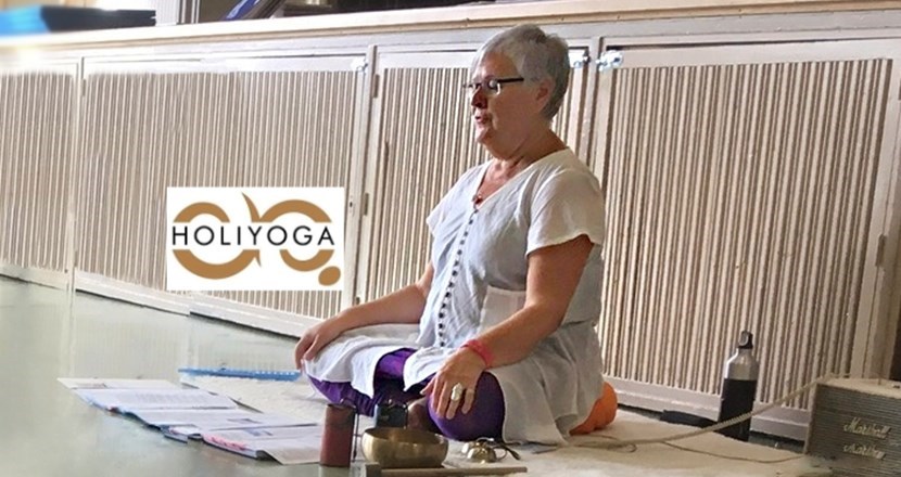 En bild på Karin Westrin, en medelålders kvinna som sitter på golvet i lotusställning. Foto.