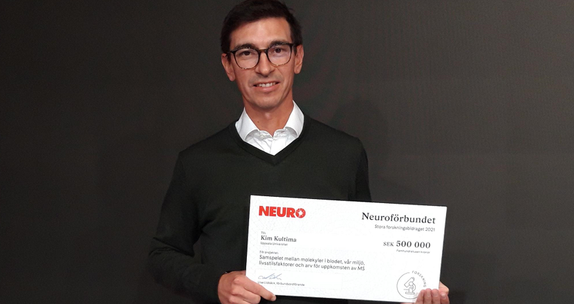 Forskaren Kim med en check från Neuro. Foto.