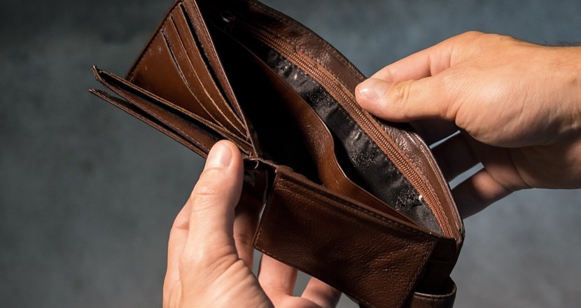 En tom brun plånbok som hålls upp av två händer. Foto.