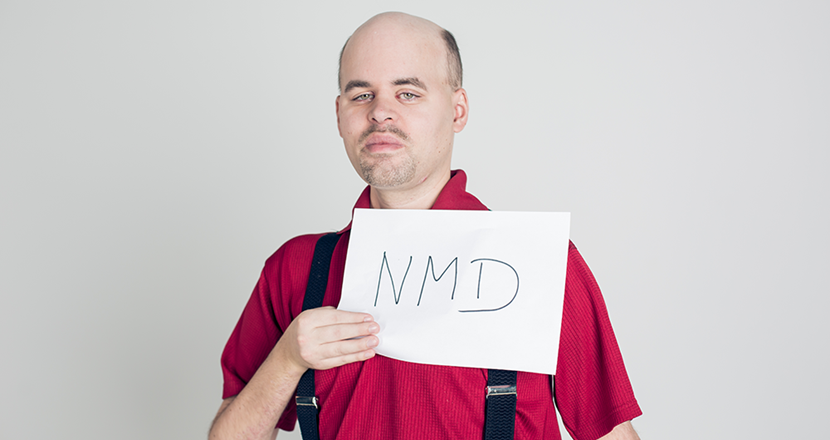 Bild på Mikael som håller en skylt med förkortningen NMD. Foto.