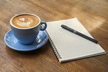Kopp kaffe med anteckningsblock och penna bredvid