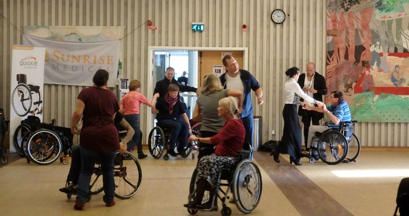 Man ser flera par dansa rullstolsdans med stående partners