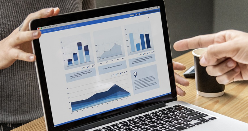 Person pekar på datorskärm med olika grafer och staplar.