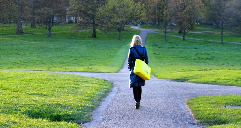 En kvinna som promenerar på en gångväg och passerar en vägkorsning. Foto.