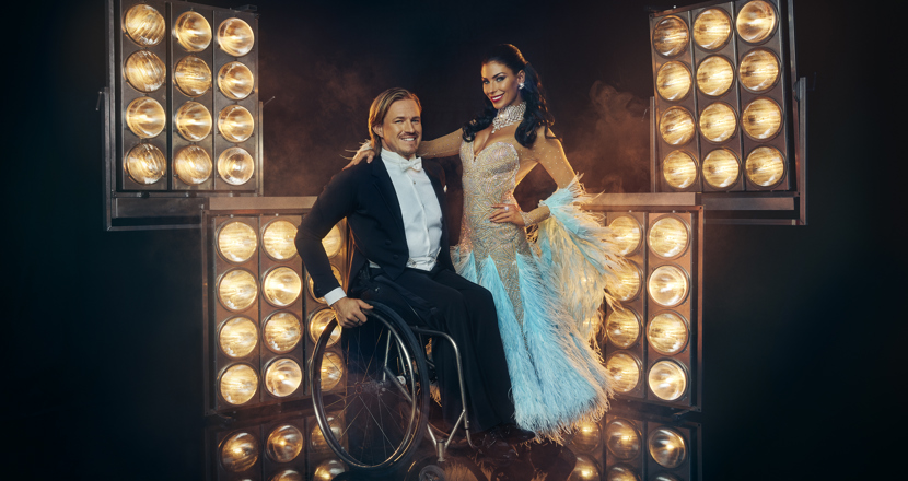 Två dansare i finkläder. En i rullstol och en stående. Foto.