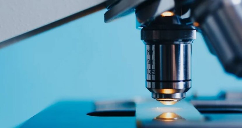 Ett mikroskop i närbild med blå bakgrund. Foto.