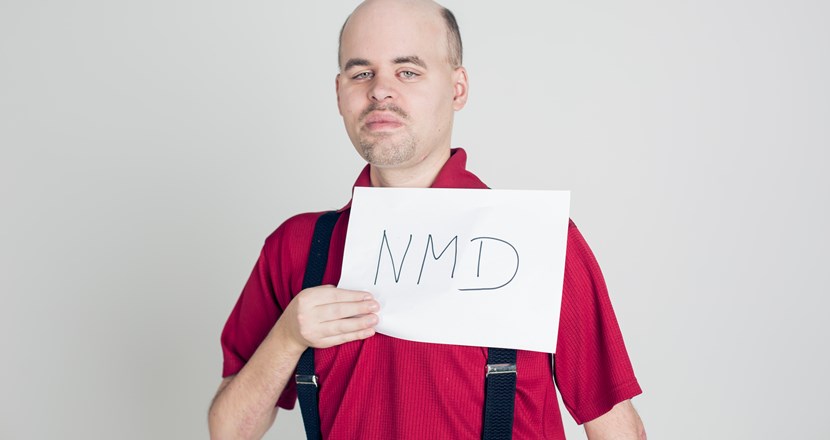 Man som håller en skylt med texten NMD. Foto.