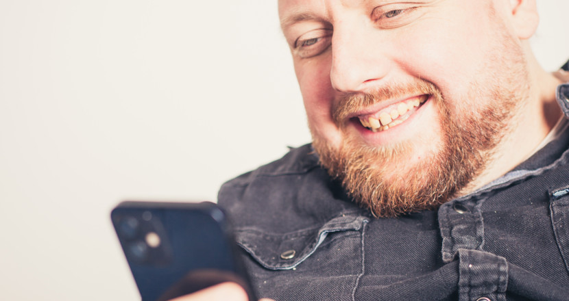 En man som tittar i sin mobil. Foto.