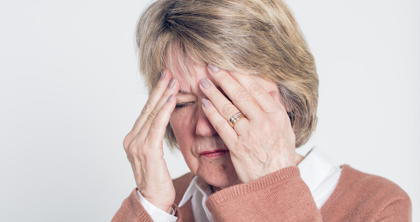 Närbild på kvinna som håller händerna för sitt ansikte och försöker minnas.