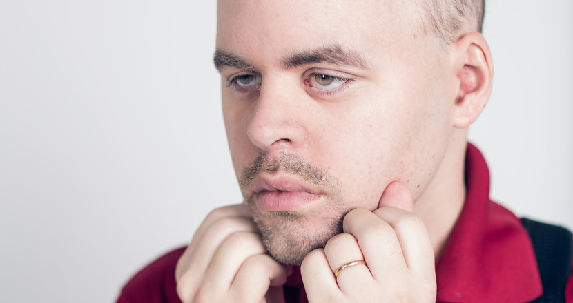 Närbild på man som stödjer hakan i händerna och tänker.