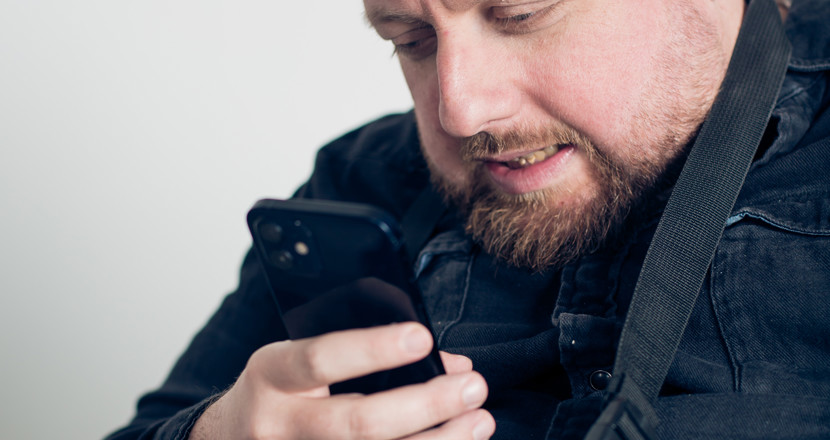 En man som tittar i sin mobiltelefon. Han ser frustrerade ut. Foto.