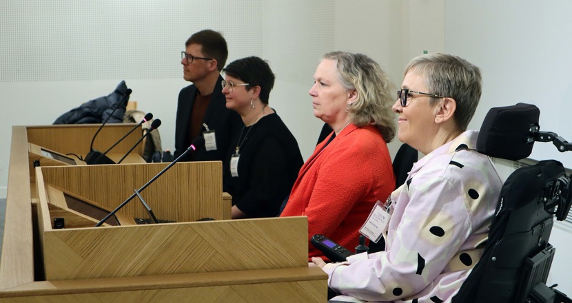 Fyra personer på rad på ett podium. Foto.
