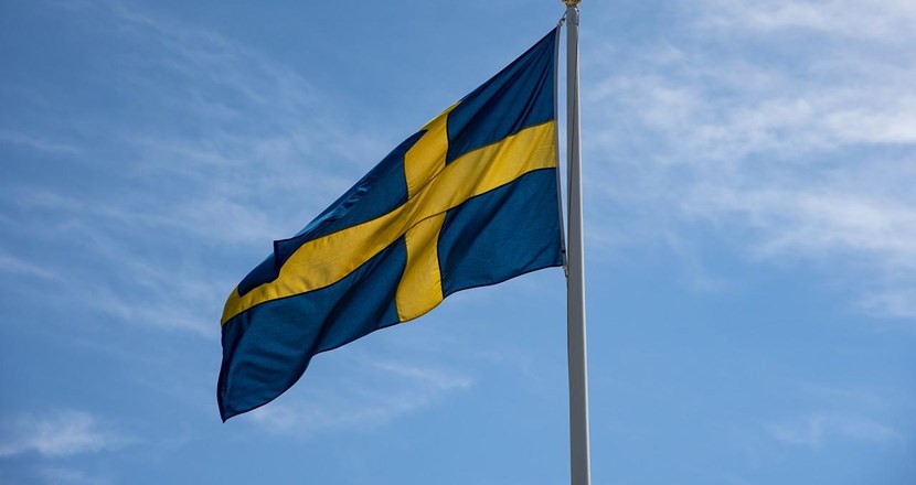 En svensk flagga mot blå himmel. Foto.