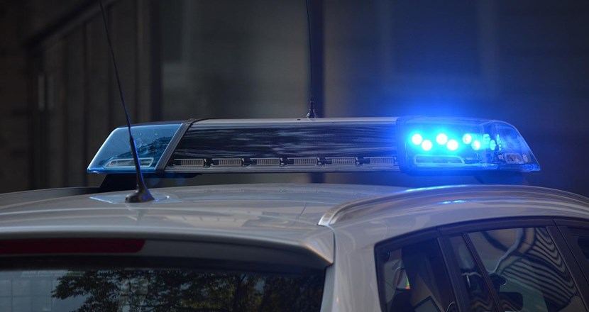 Taket på en polisbil med blåljus påslaget. Foto.