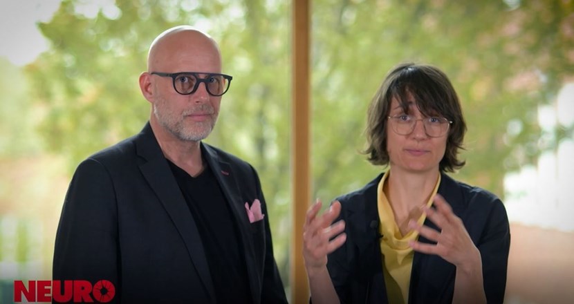 En man och en kvinna, båda med glasögon och i svarta kavajer. Foto.