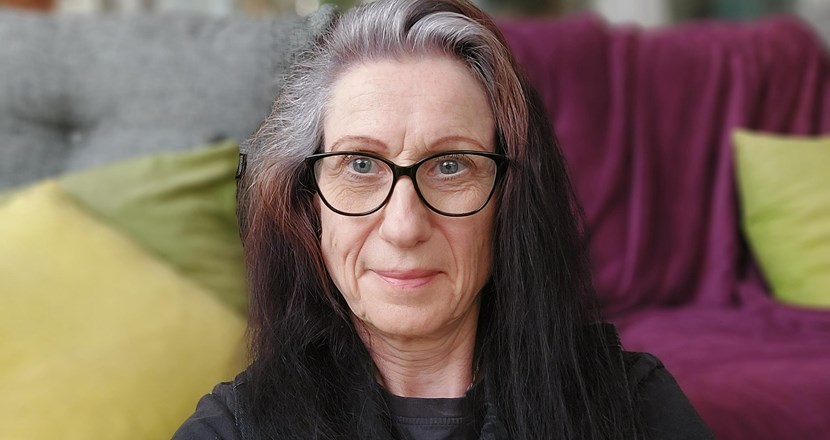 Porträttbild på Susanne med färgglada kuddar i bakgrunden. Foto.