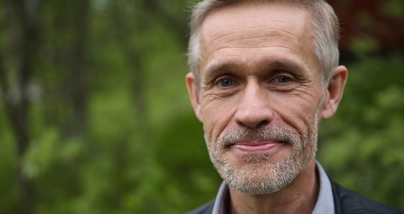 Porträttbild på Anders mot grönskande bakgrund. Foto.