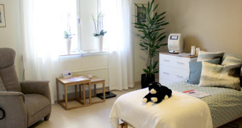 Ett sovrum inrett i ljusa färger med en katt på sängen. Foto.