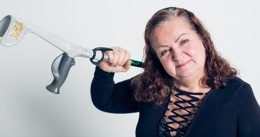 En kvinna som lyfter sin krycka över axeln. Foto.