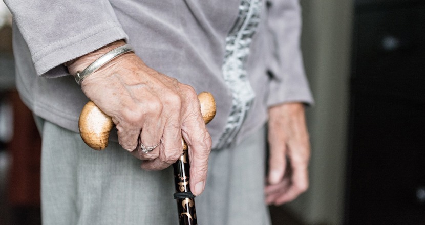 Närbild på en gammal hand på en käpp. Foto.