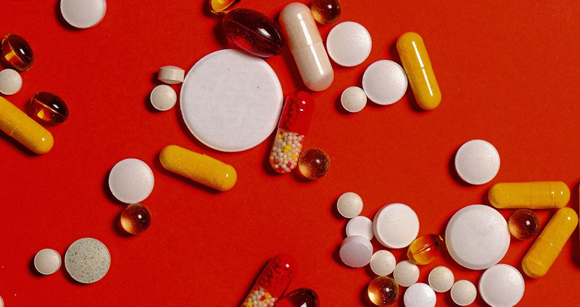 Tabletter utspridda på en röd bakgrund. Foto.