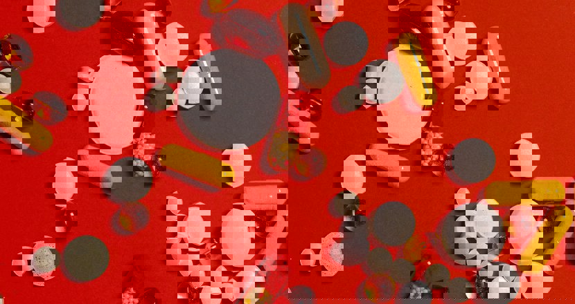 Tabletter utspridda på en röd bakgrund. Foto.