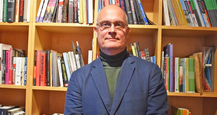 Man framför bokhylla. Foto.