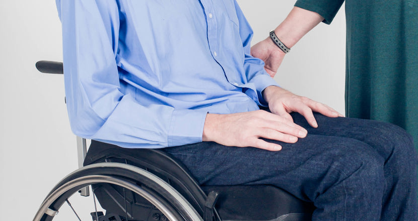 Person som sitter i rullstol och en person som ger assistans.