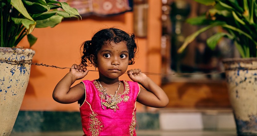 En liten indisk flicka i en ceriserosa klänning. Foto.