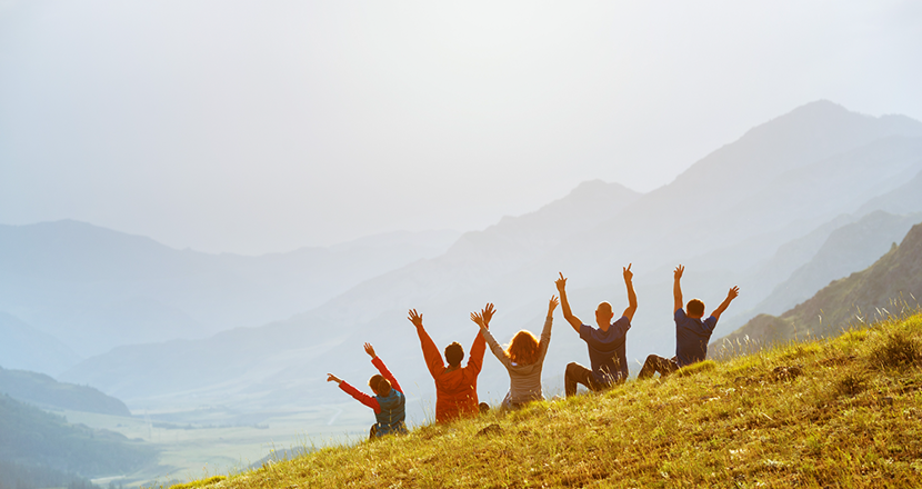 Fem personer på rad med ryggen mot kameran och händerna upp i luften. Foto.