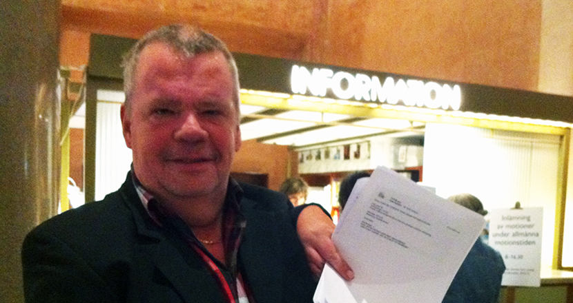 En bröstbild på en medelålders man, som håller i några papper. Foto.