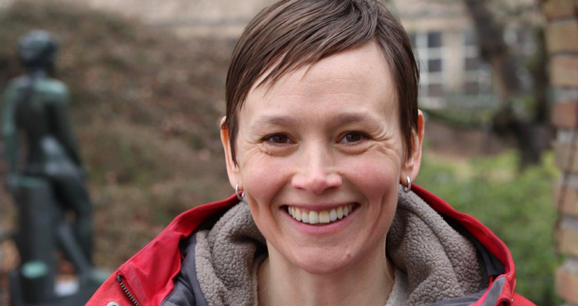 Porträttbild på Katarina Gustafsson mot grönskande bakgrund. Foto.