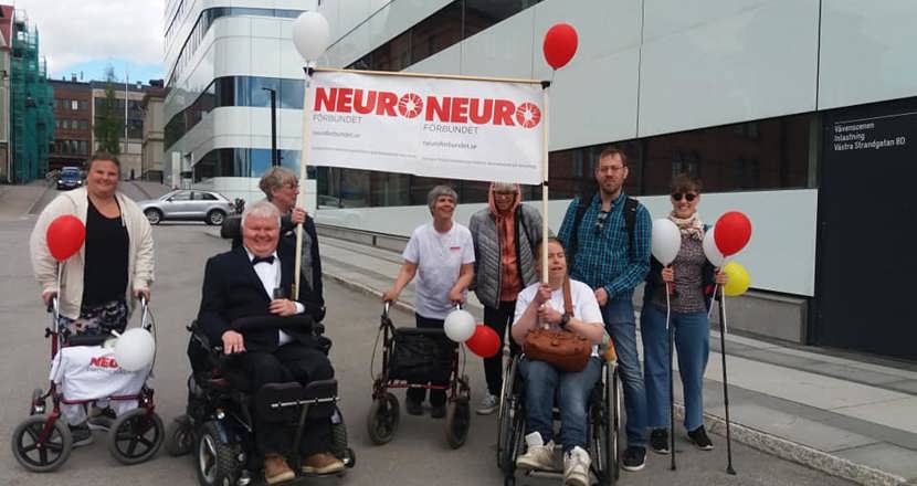 Personer går i promenaden 2022 med en Neurobanderoll